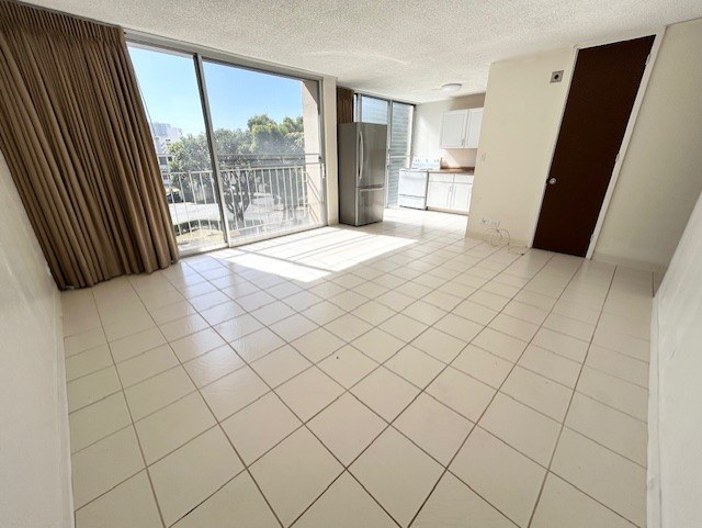A spacious room with a view of the outside through the sliding glass doors.